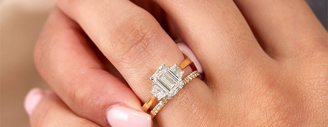 Three-stone emerald cut diamond engagement ring with tapered baguette side stones on gold band